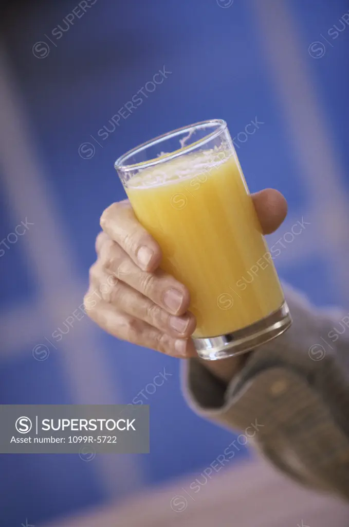 Person holding a glass of orange juice