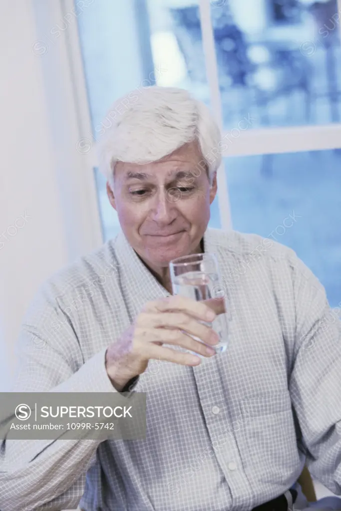 Elderly man holding a glass of water