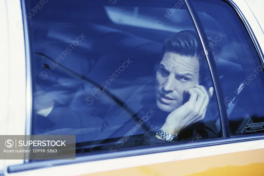 Businessman sitting in a taxi talking on a mobile phone