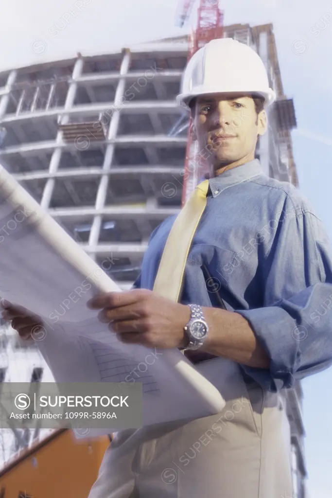 Portrait of an engineer standing at a construction site holding blueprints