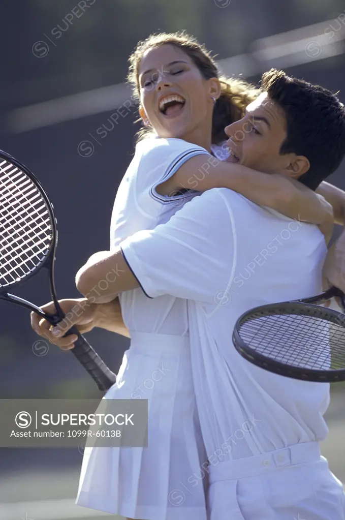 Young couple hugging each other at a tennis court