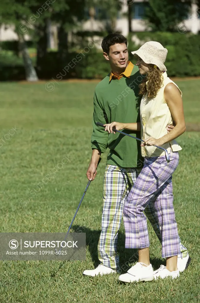 Mid adult man and a mid adult woman walking on a golf course