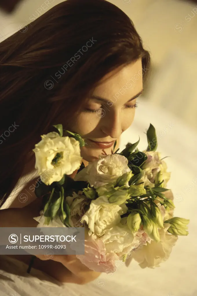 Young woman lying on a bed smelling flowers