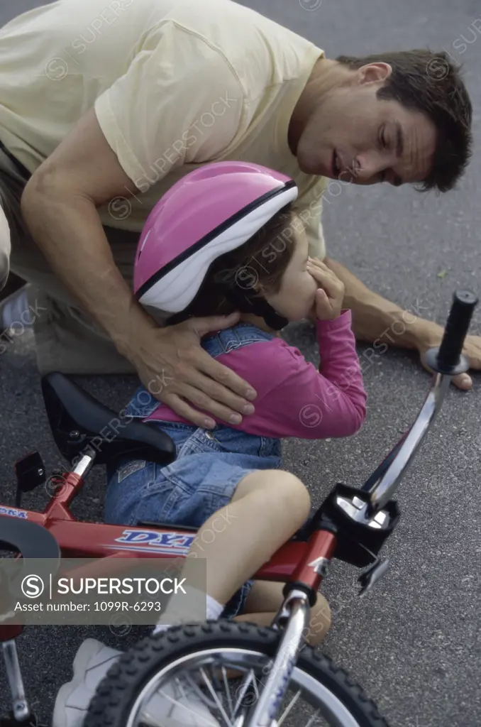 Father consoling his daughter after a fall from her bicycle