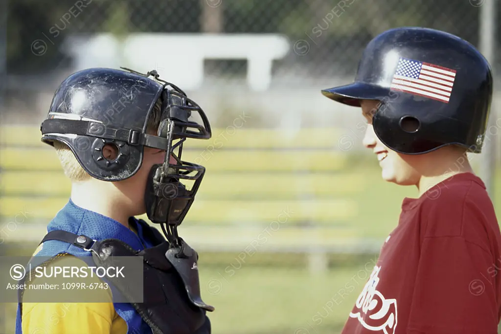 Two boys in baseball uniforms looking at each other
