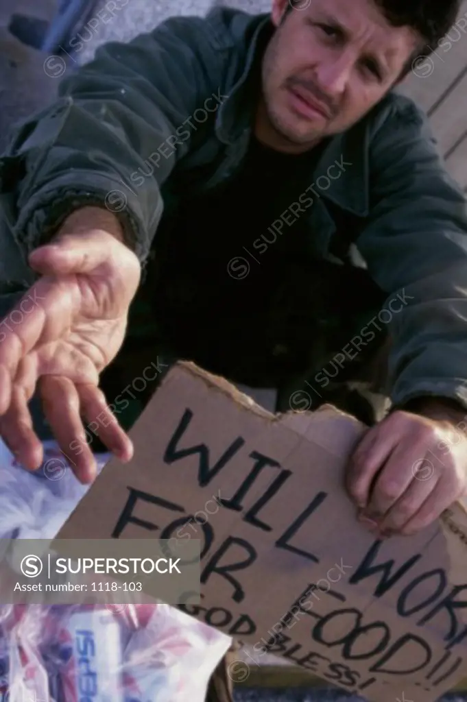 Portrait of a mid adult man on the street holding a cardboard sign