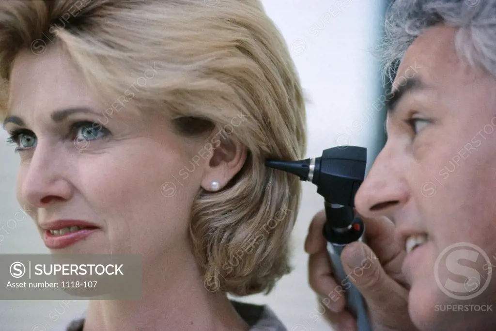 Close-up of a male doctor examining a female patient's ear
