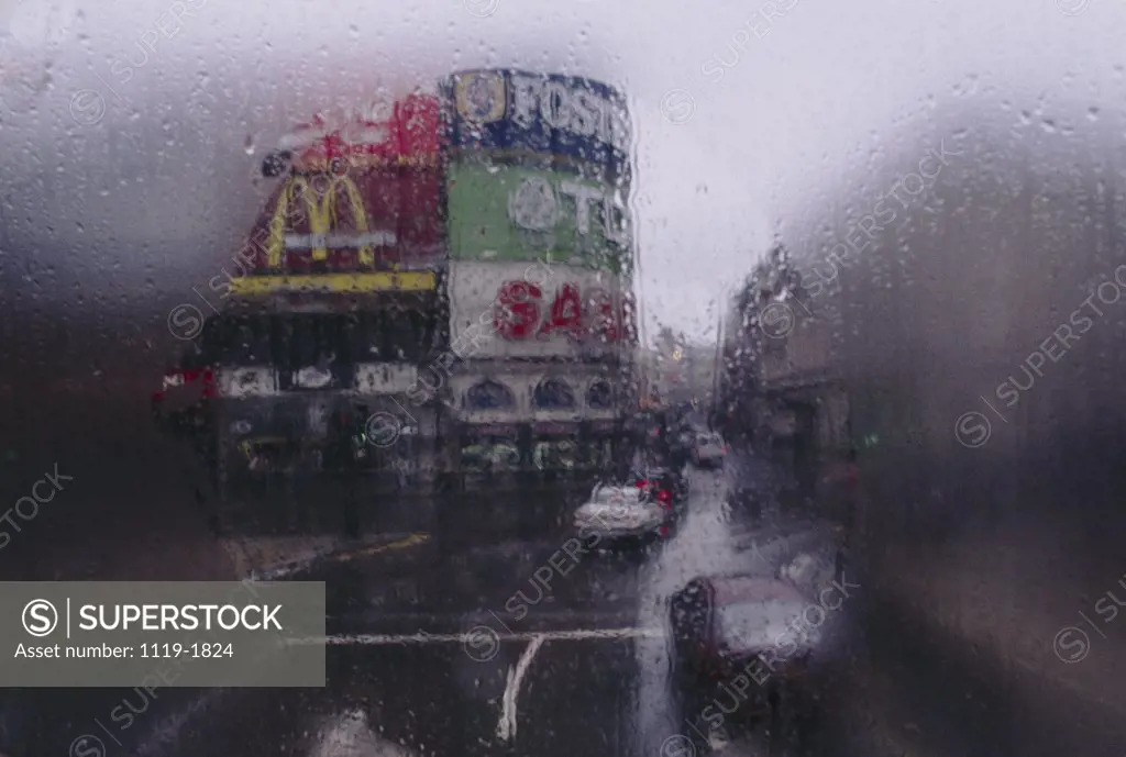Traffic on road in rain, Piccadilly Circus, London, England