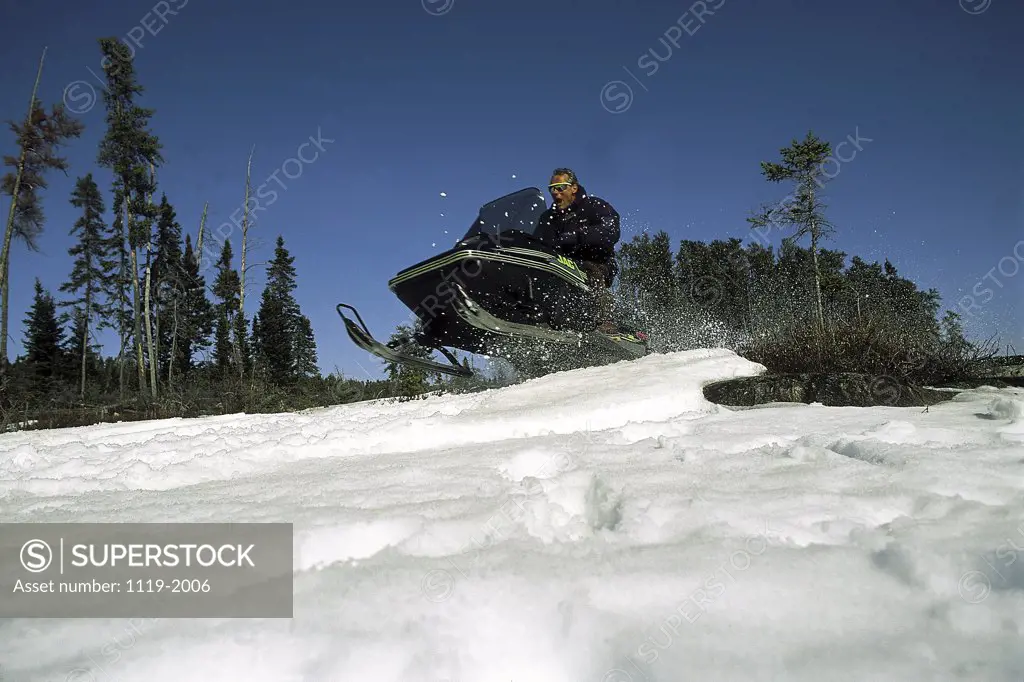Low angle view of a young man riding a snowmobile, Ontario, Canada