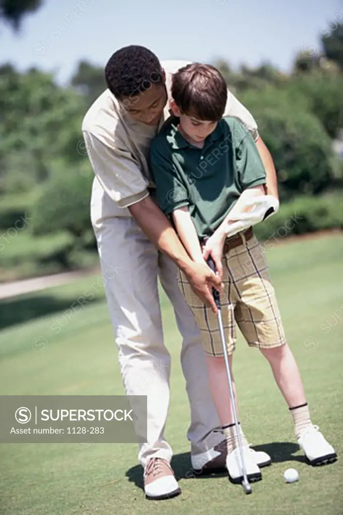 Young man teaching golf to a teenage boy on a golf course