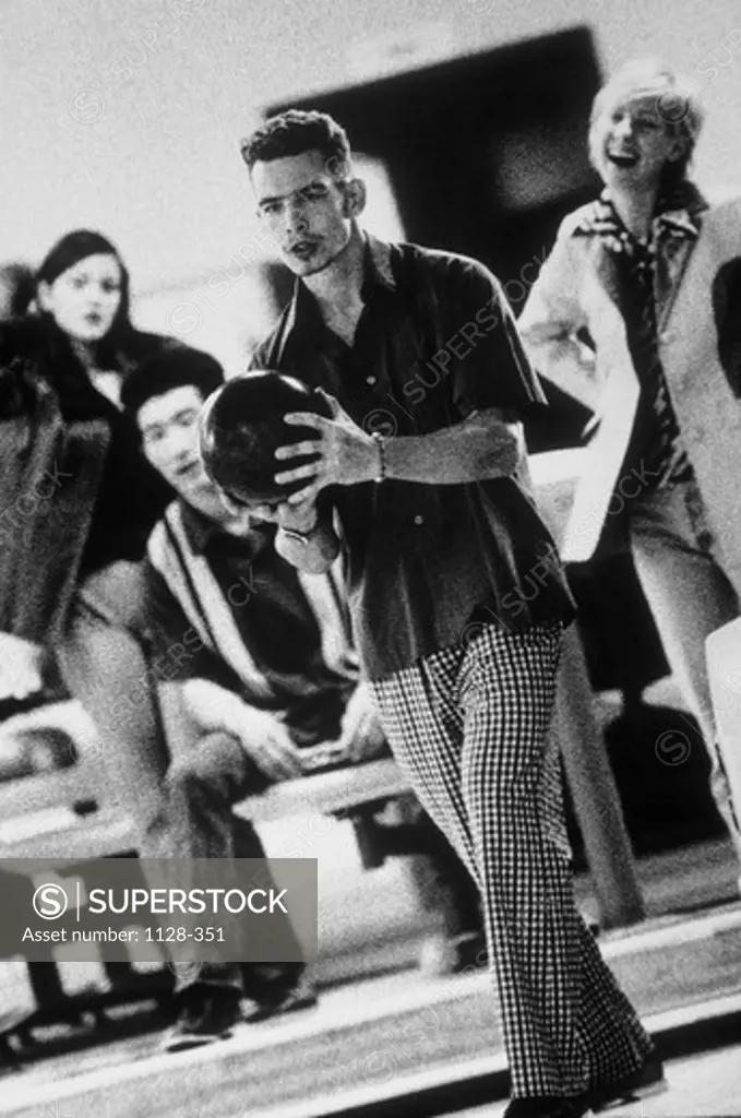Young man holding a bowling ball in a bowling alley