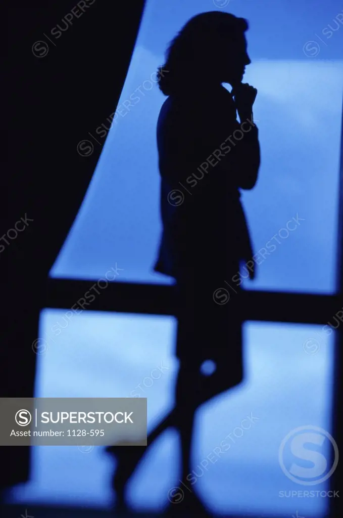 Silhouette of a businesswoman looking out of a window