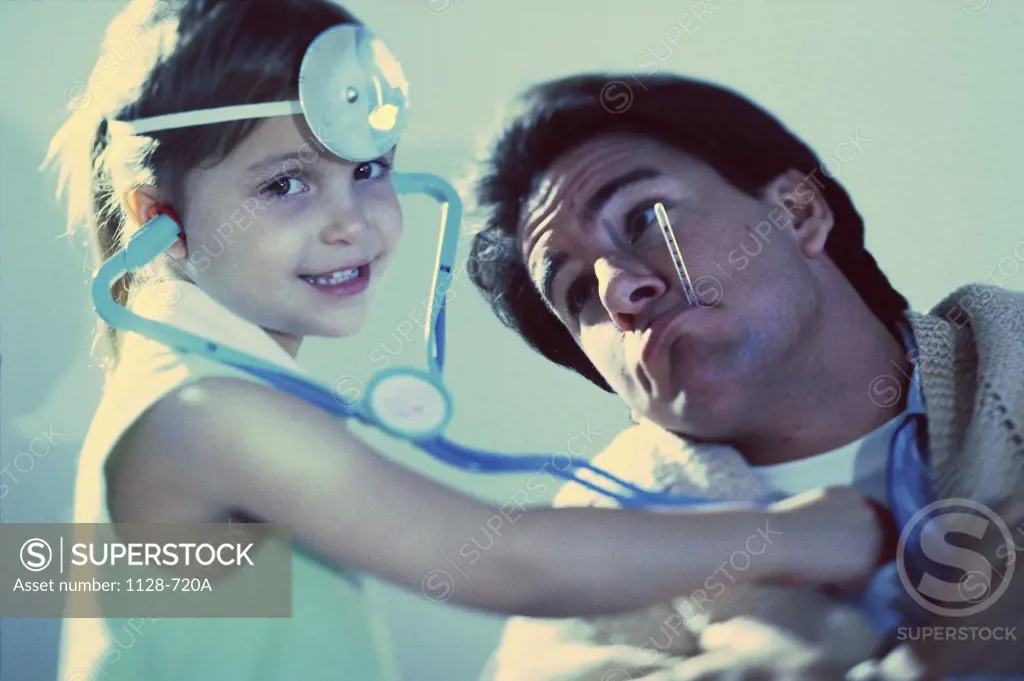 Portrait of a girl pretending to be a doctor with her father as a patient