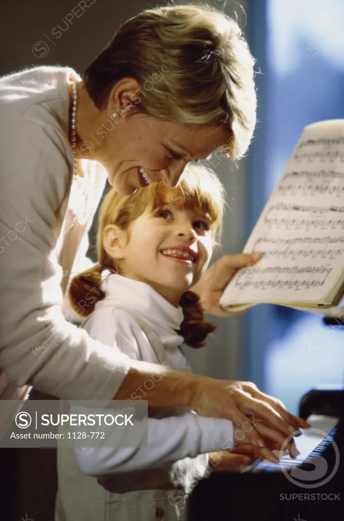 Grandmother teaching her granddaughter the piano