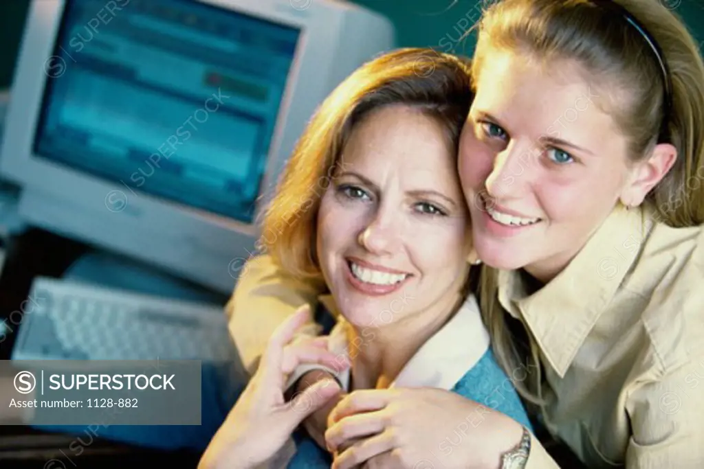 Portrait of a teenage girl hugging her mother from behind and smiling