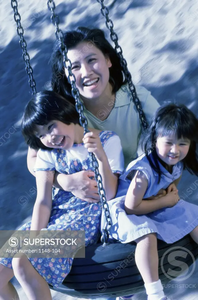 Portrait of a mother sitting on a tire swing with her son and daughter