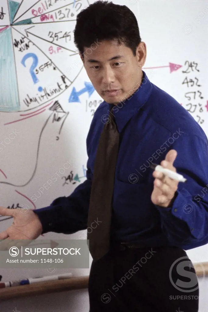 Side profile of a businessman explaining a pie chart on a whiteboard