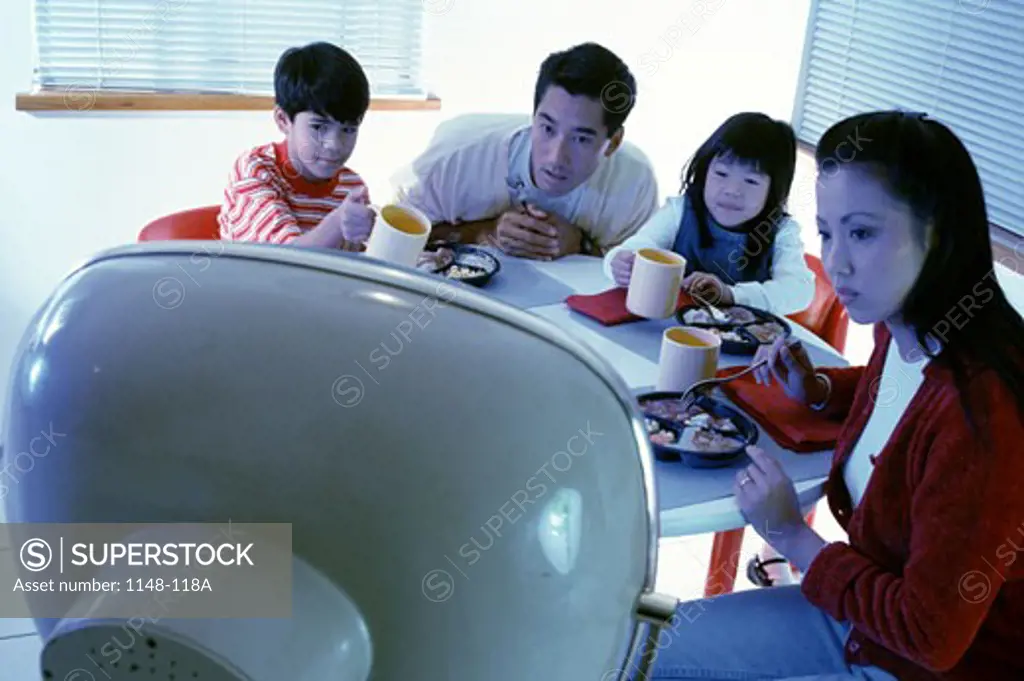 Family watching television while having breakfast