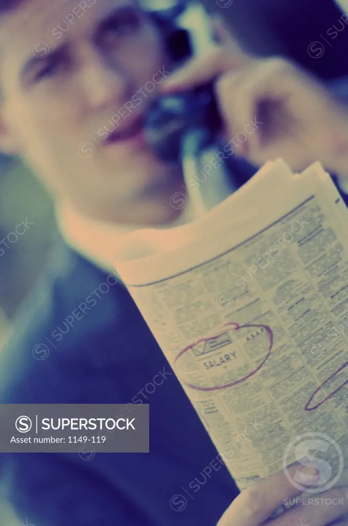 Businessman talking on a telephone holding a newspaper