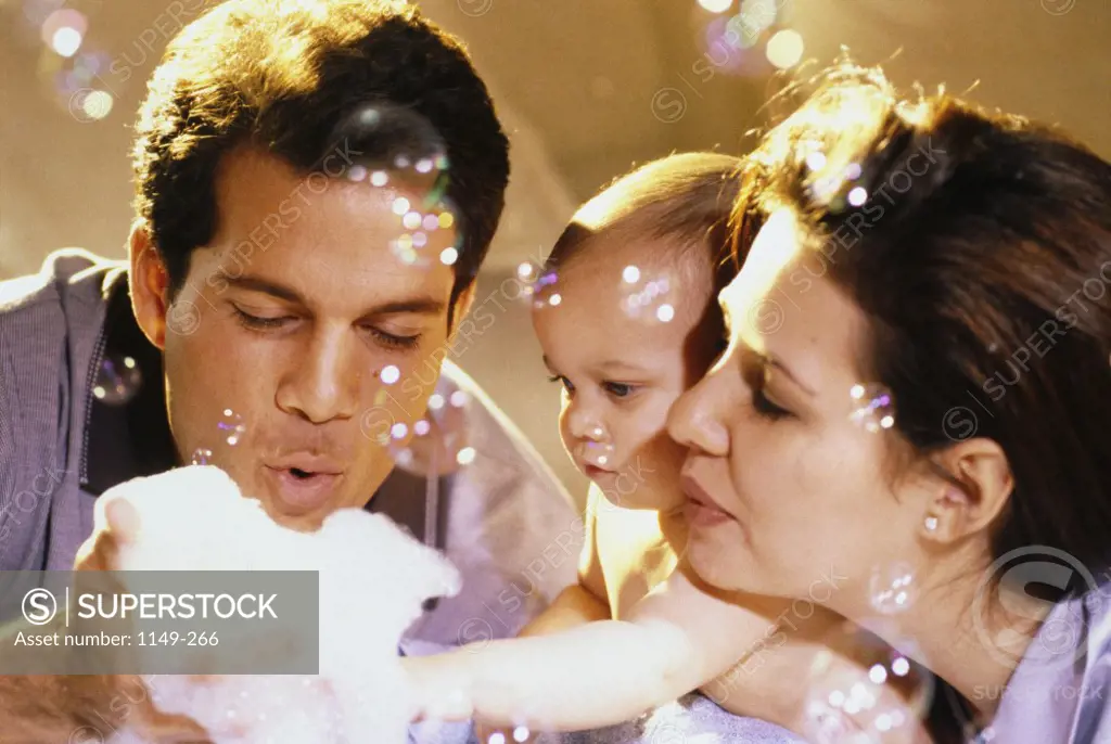 Close-up of parents and their baby boy playing with soap bubbles