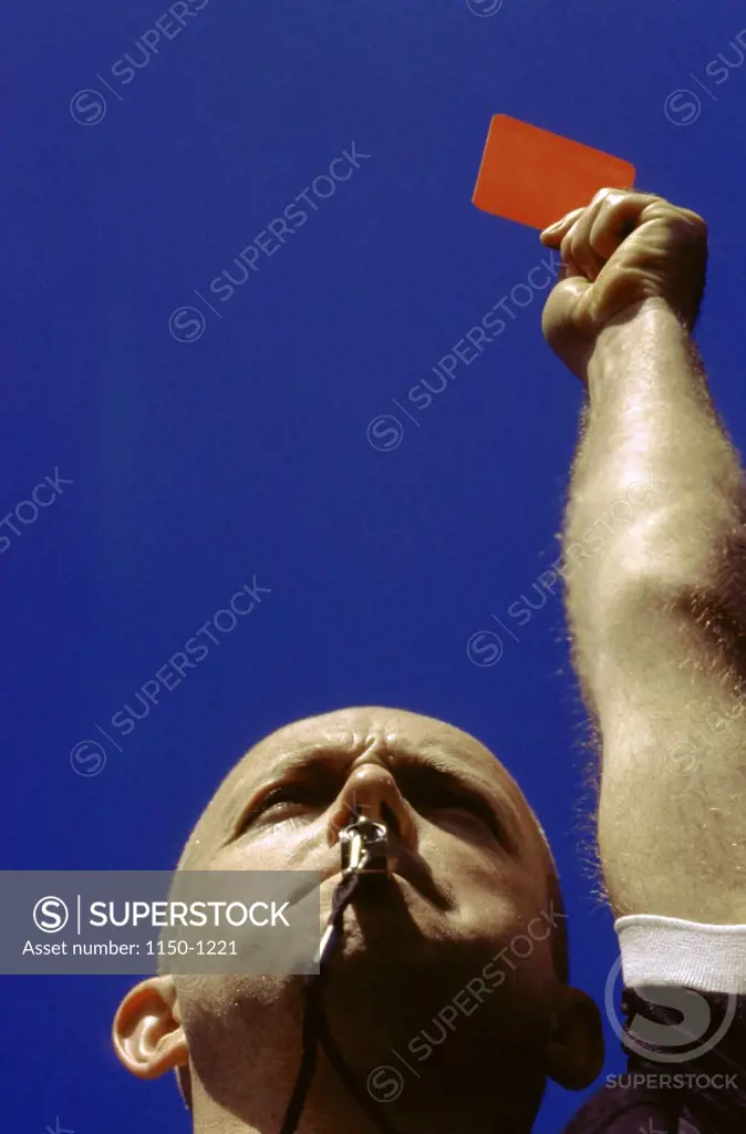 Low angle view of a referee holding up a red card