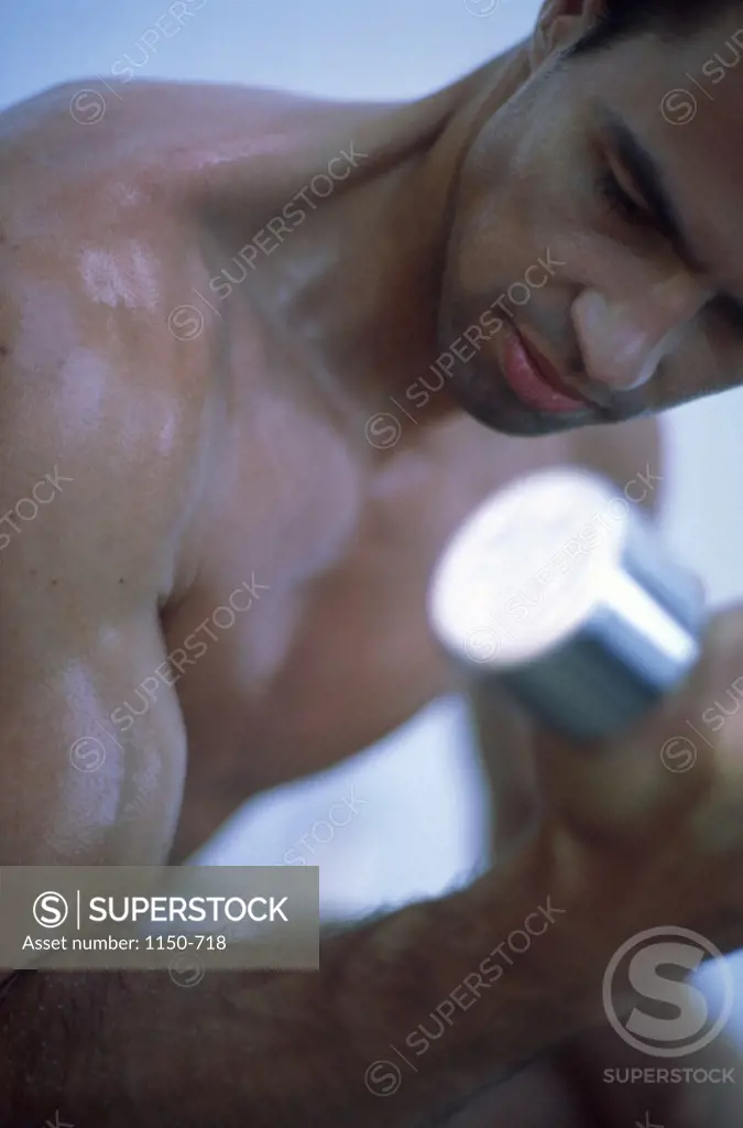 Close-up of a young man exercising with dumbbells