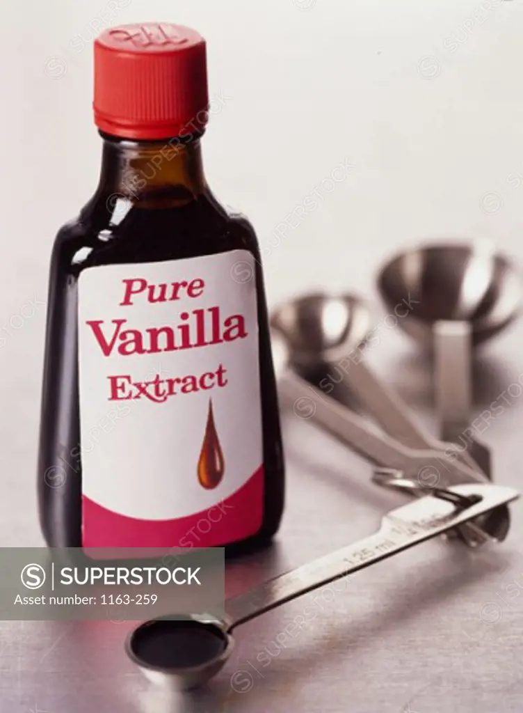 Close-up of a bottle of vanilla extract with measuring spoons
