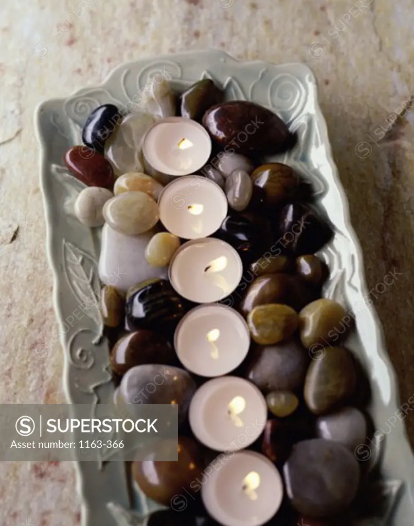 High angle view of burning candles with pebbles on a tray