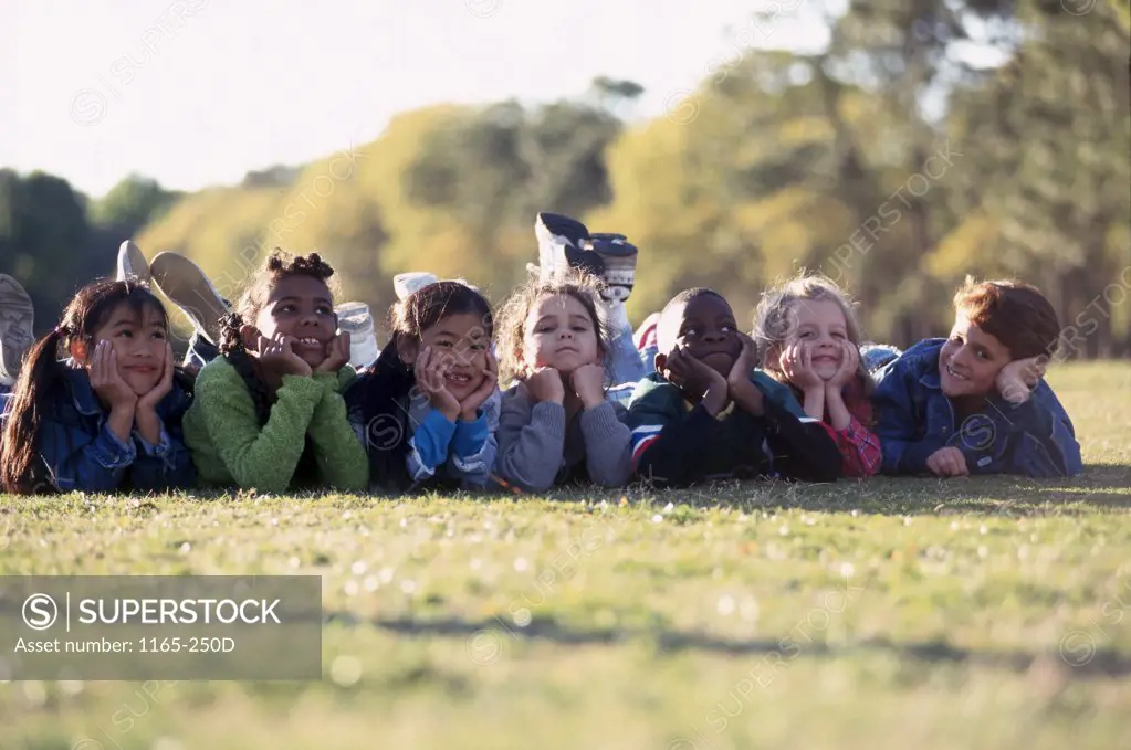 Group of children lying side by side on the grass