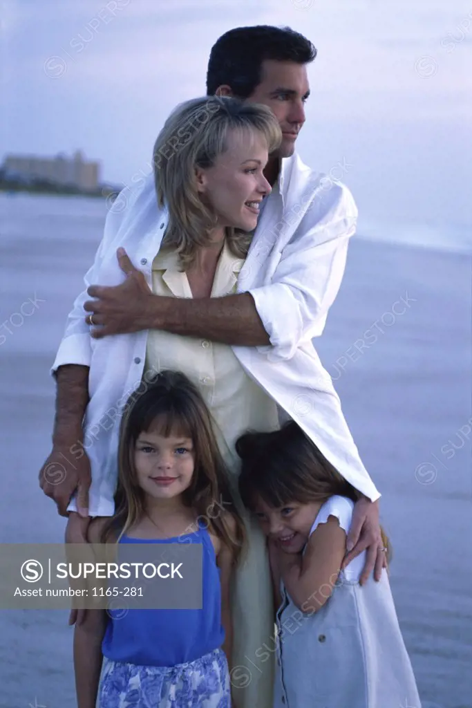Young couple on the beach with their two daughters