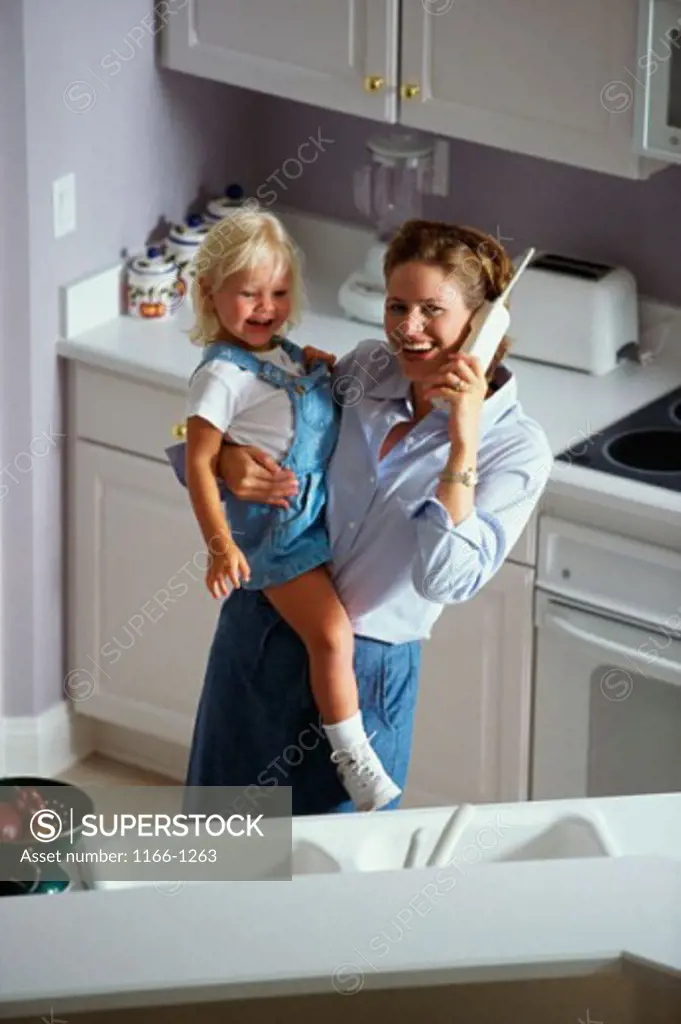 High angle view of a mother carrying her daughter and talking on a cordless phone