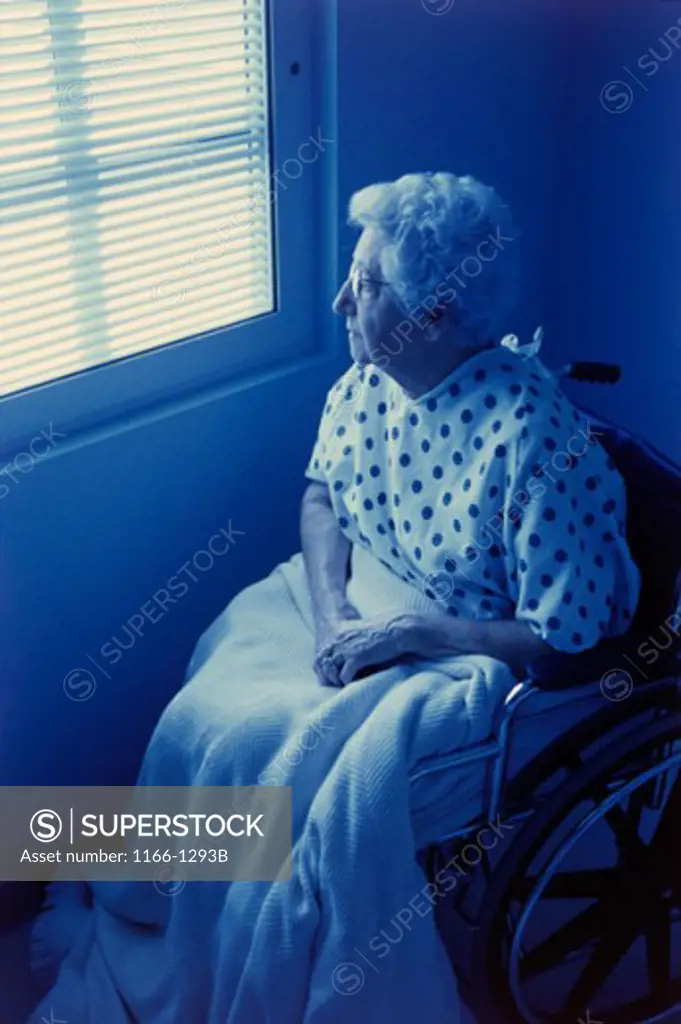 Senior woman sitting in a wheelchair looking out of a window