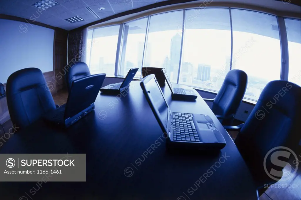 Laptops on a conference table in an empty conference room