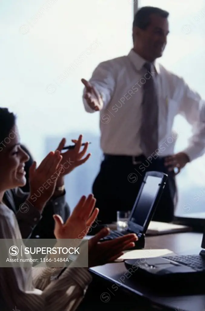 Businessmen and businesswomen applauding in a meeting