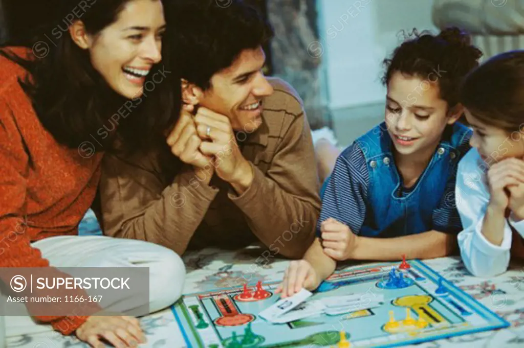 Young couple and their two daughters playing a board game