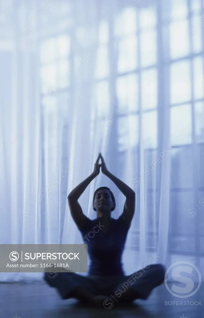 Silhouette of a mid adult woman sitting in the lotus position