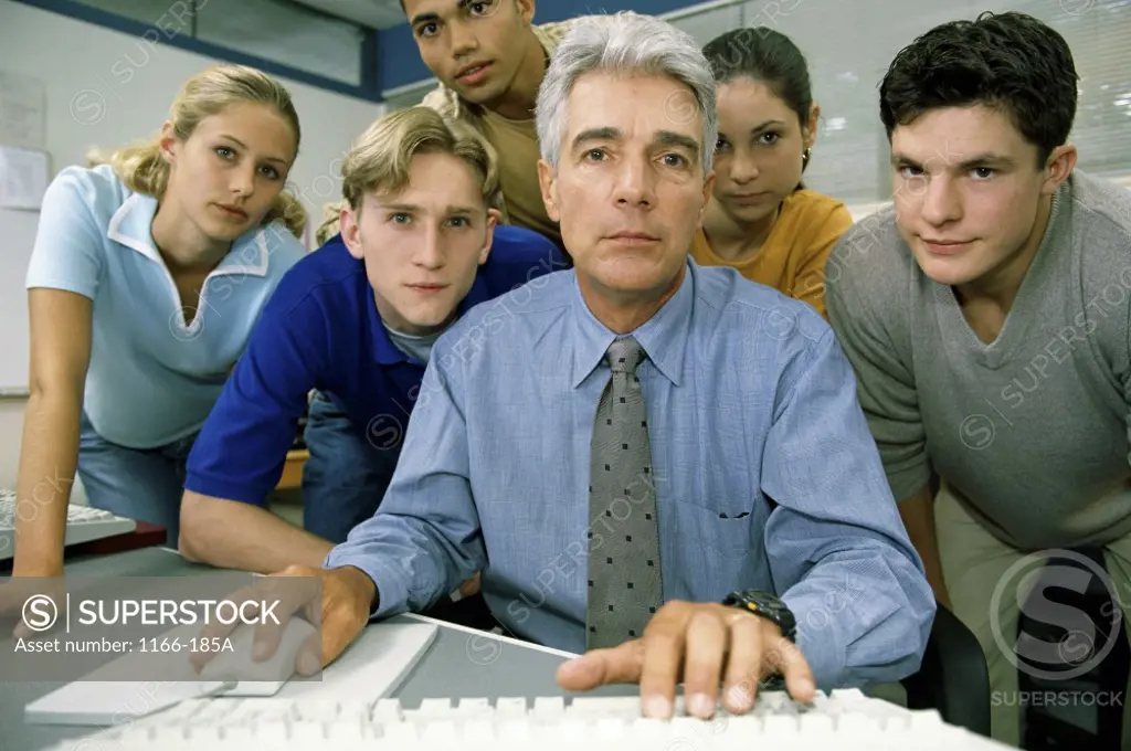 Male teacher and his students in front of a computer