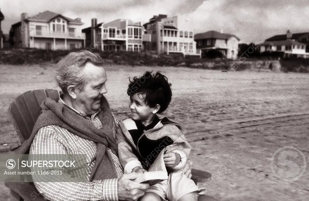 A child sitting with his grandfather on the beach