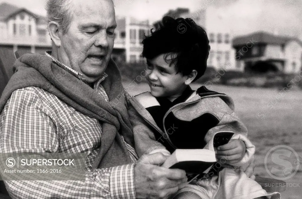 Grandfather reading a book with his grandson