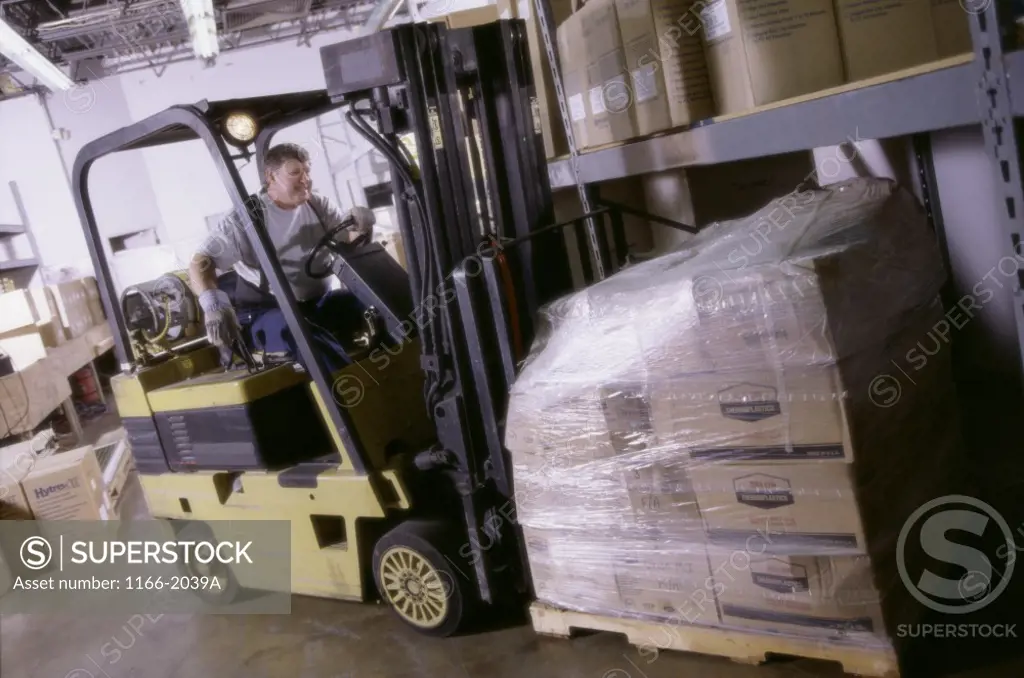 Young man driving a forklift in a warehouse