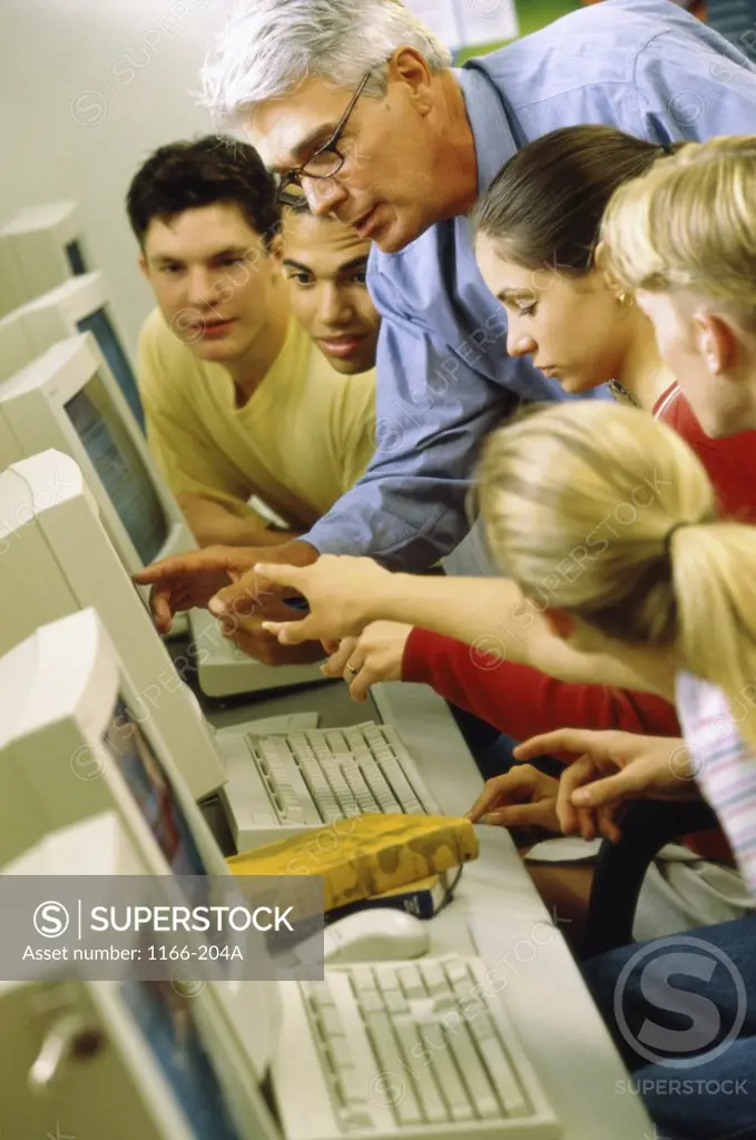 Male teacher and his students in front of computers