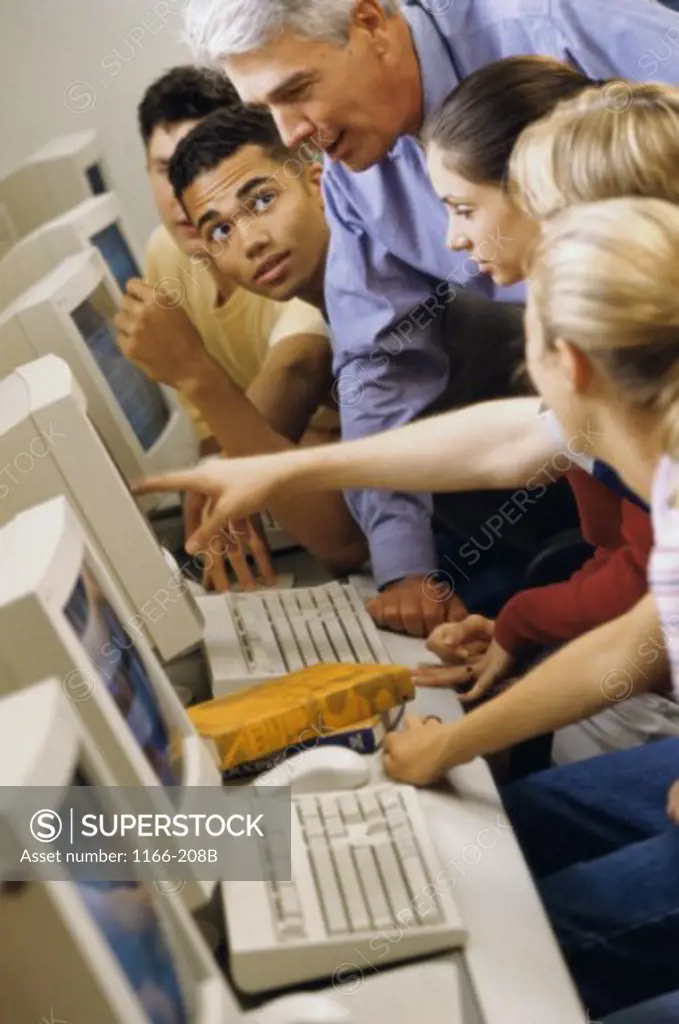 Male teacher and his students in front of computers