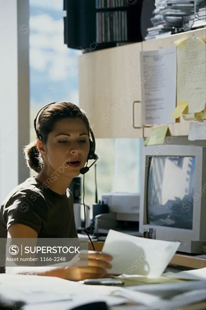 Female customer service representative wearing a headset and reading documents