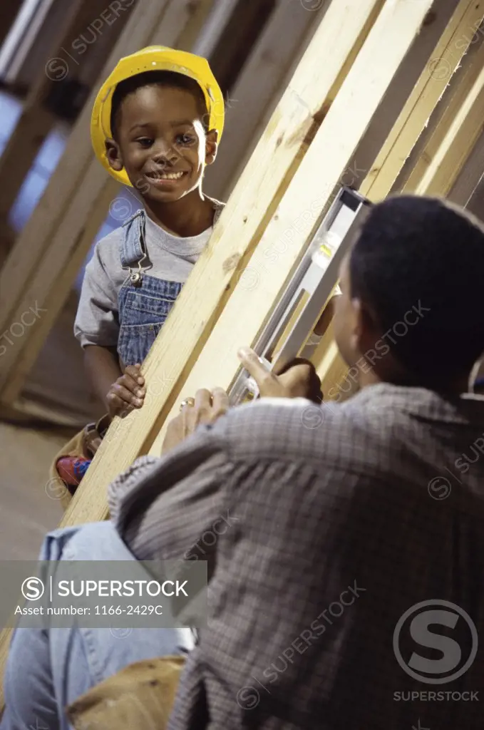 Young boy in a hard hat smiling at his father