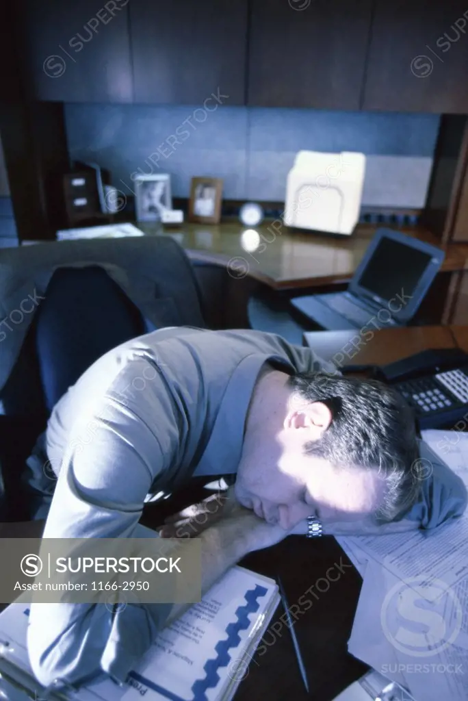 High angle view of a businessman resting his head on a desk