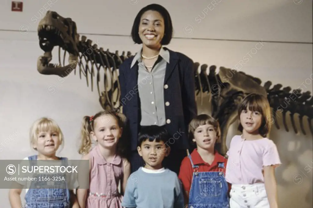 Portrait of a group of children standing in a museum with their teacher