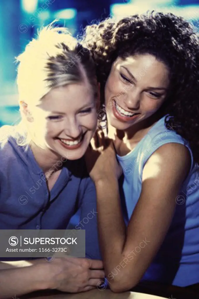 Two young women sitting together smiling