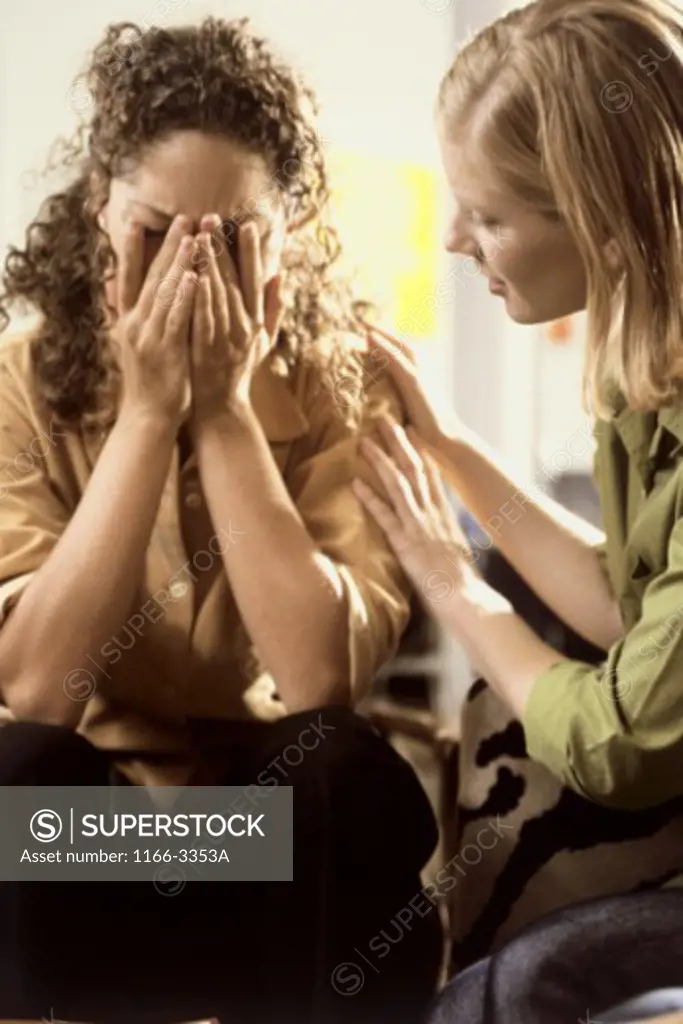 Young woman consoling another
