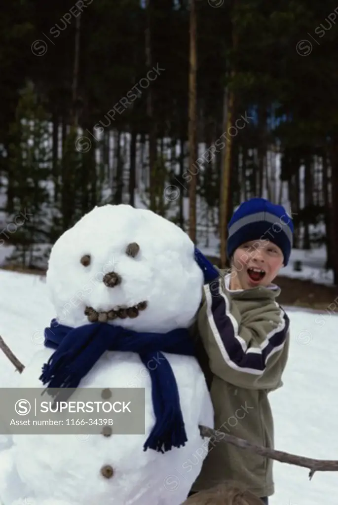 Boy standing behind a snowman