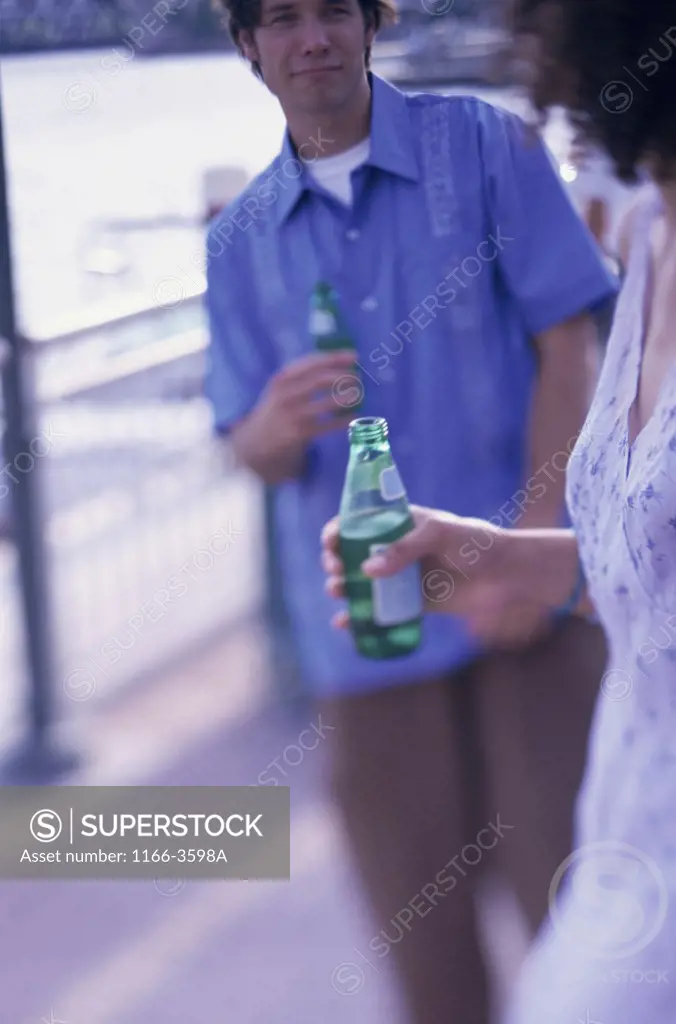 Young couple walking together holding bottles of beer